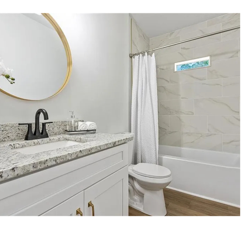 Timeless Elegance: Batic Countertops, Gold Mirror & White Tub Serenity