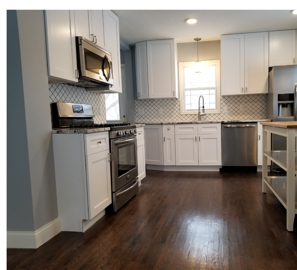 Bright Whites & Rich Wood Floors: A Classic Kitchen UpdateThis kitchen features crisp white cabinetry, a contrasting dark wood floor, and a stylish patterned backsplash for a fresh, timeless appeal.