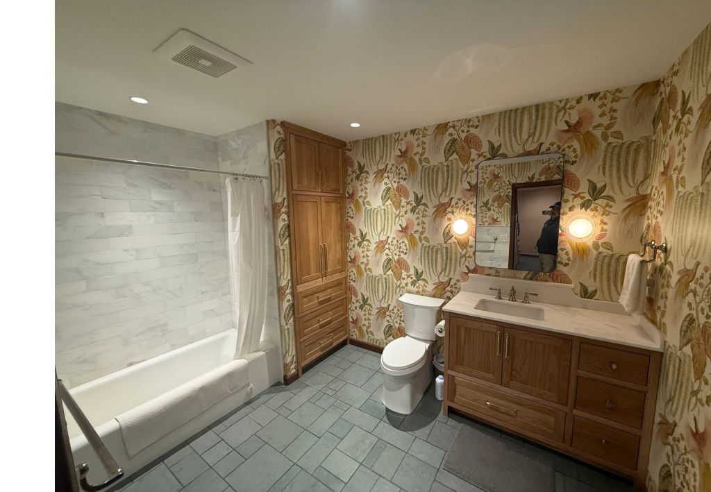 Patterned Sophistication: The patterned floor tiles and subtle wallpaper introduce visual interest and depth to this refined bathroom design.